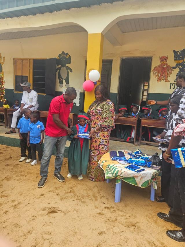 A nursery graduate receiving a wrapped gift from members of staff on graduation day
