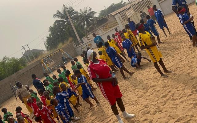 Pupils lined up in red, blue, yellow and green house colours on the sports field