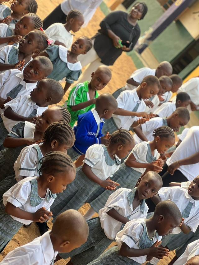 Pupils clapping and singing together during morning devotion on the school compound