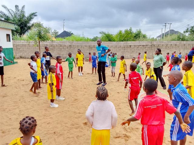 Pupils in house colours warming up with a teacher on the school sports field